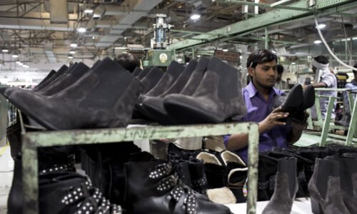 A worker performs quality-control inspections on shoes on the assembly line